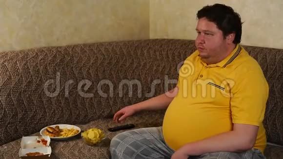 胖子坐在家里的沙发上看电视吃快餐视频的预览图