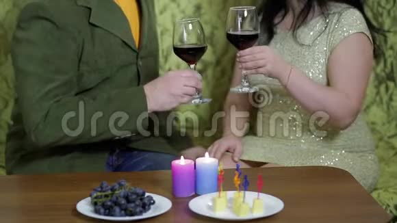 一对相爱的幸福夫妇坐在桌子旁的沙发上喝红酒视频的预览图