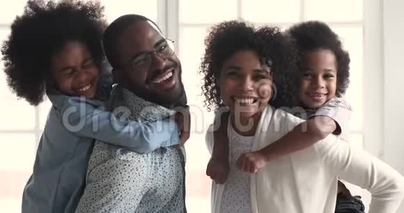 快乐的非洲父母驮着孩子看相机家庭肖像视频的预览图