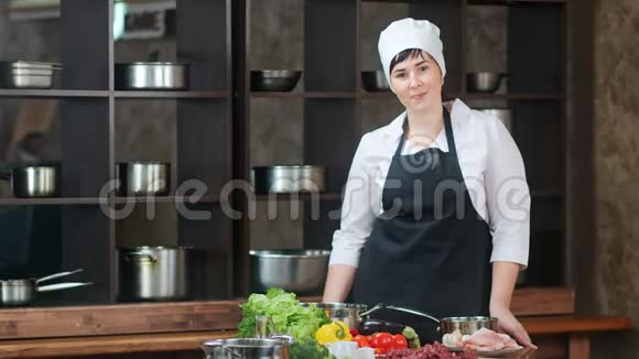 微笑女厨师穿围裙在餐厅厨房内部摆姿势中型摄影机视频的预览图