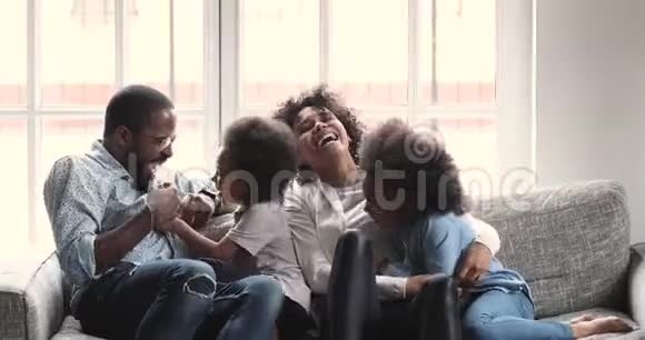 欢乐多情的非洲家庭笑着拥抱在沙发上视频的预览图