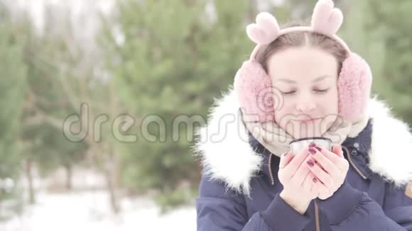 一个女人在穿过冬天的公园时喝着热茶视频的预览图