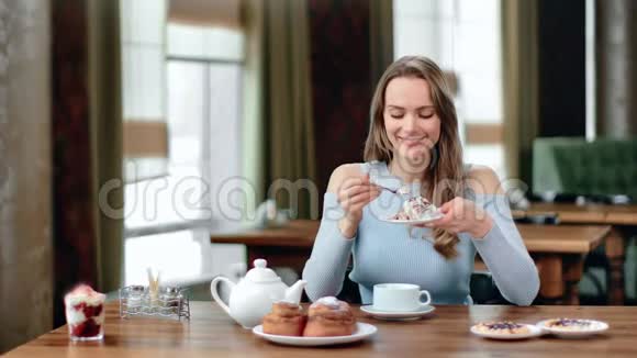 微笑的年轻女士在咖啡馆吃开胃的糕点甜点的肖像中型摄影机视频的预览图