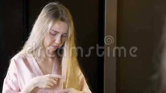 不快乐的女人头发干脆照镜子检查她的小贴士视频的预览图