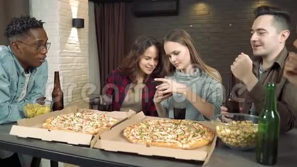 快乐的多民族朋友一起在家的客厅喝啤酒吃披萨玩得开心视频的预览图