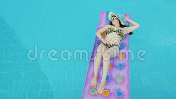 完全放松没有工作和手机女孩在蓝色游泳池的床垫上日光浴视频的预览图