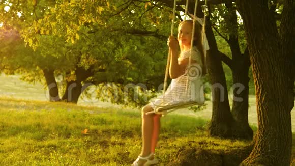 在日落公园的橡树枝上孩子们用绳子摆动着女孩笑高兴快乐的童年概念年轻女孩视频的预览图