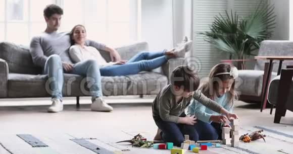 孩子们一边玩耍一边放松的父母在客厅内部休息视频的预览图