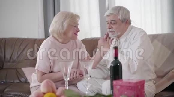 侧面看美丽的白种人老年妇女抚摸丈夫脸用爱看着他快乐成熟的男人视频的预览图