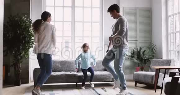 快乐的年轻夫妇和小女儿在客厅跳舞视频的预览图