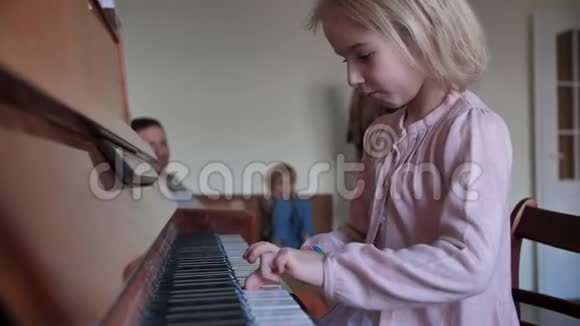 一个六岁的女孩和她的家人一起弹钢琴她的父母为她鼓掌视频的预览图