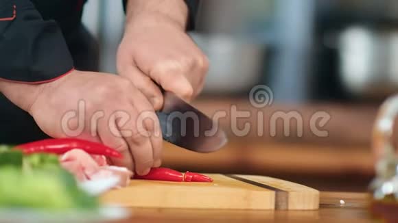 男厨师手里拿着黑色的制服在木板上切碎辣椒近距离拍摄4k红色相机视频的预览图