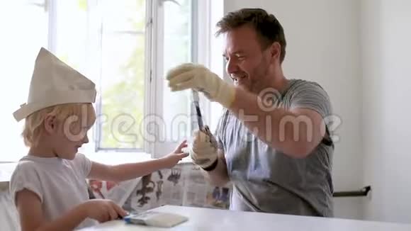 成熟的男人和小男孩一起在房间修理期间玩油漆刷视频的预览图
