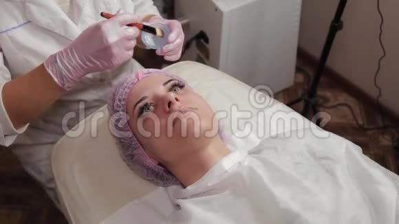 专业美容师用刷子在客户的脸上涂上口罩视频的预览图