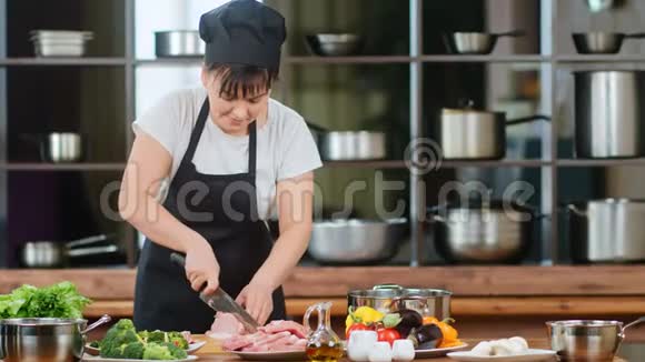 自信的女厨师在烹饪时在牛排上切新鲜的生鸡片4k龙红相机视频的预览图