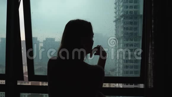 剪影悲伤孤独女人触摸玻璃窗下雨天视频的预览图