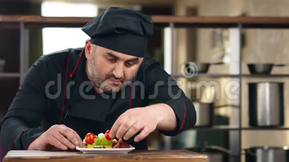 自信的大胡子男厨师把西红柿放在蔬菜混合物上拍摄红鸦4k影院视频的预览图