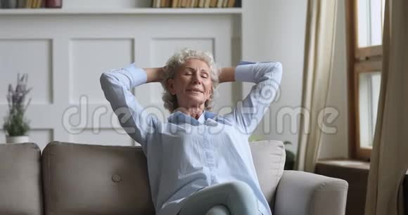 快乐健康的老妇人闭着眼睛在沙发上放松视频的预览图