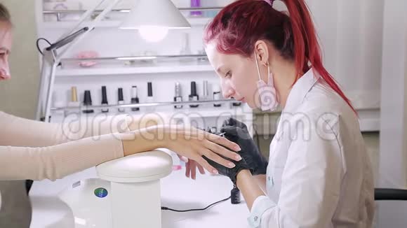 在美容院带手套的女美甲师在涂胶前先把顾客的指甲擦掉视频的预览图