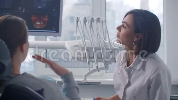 一位正畸医生在坐在椅子上的病人讨论核磁共振扫描视频的预览图