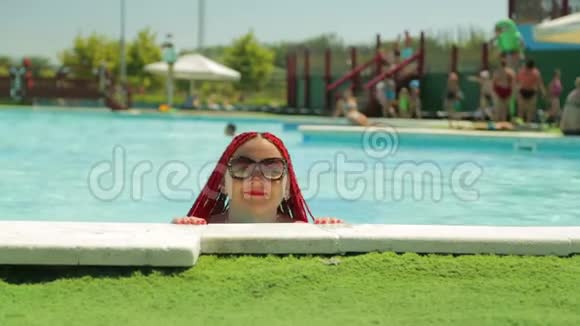 在度假时一个红头发的快活的女人游到游泳池的天堂里休息视频的预览图