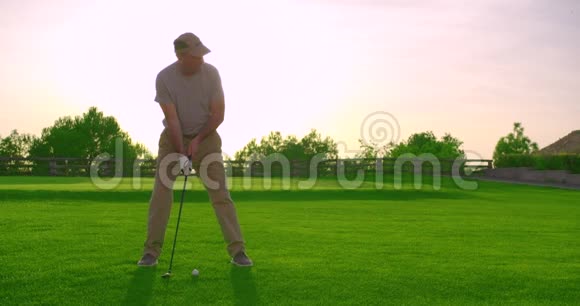 年轻英俊的高尔夫球手日落时在美丽的球场上挥杆击球视频的预览图