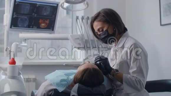 牙医治疗躺在屏幕上图片背景的椅子上的病人专业牙医视频的预览图
