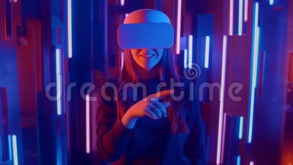 在霓虹灯中使用VR眼镜的年轻女性视频的预览图