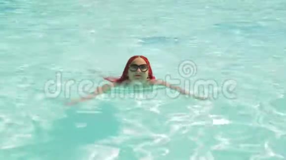 一个穿白色泳衣的年轻女子在游泳池里游泳视频的预览图