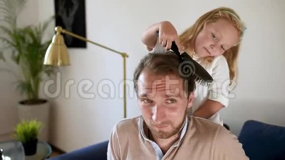 小卷发女儿给年轻英俊的父亲做了一个滑稽的发型视频的预览图
