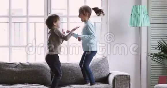 快乐的男孩和女孩在沙发上快乐地跳跃视频的预览图