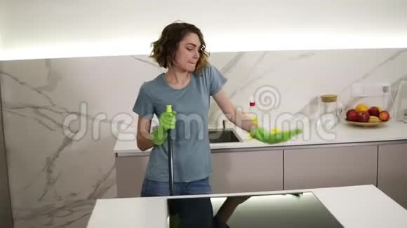 快乐的年轻女人可爱的家庭主妇用拖把洗地板在家里跳舞唱歌在厨房里享受家务视频的预览图