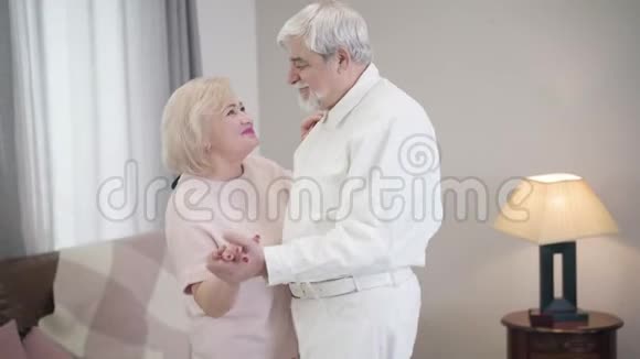 中镜头微笑成熟白种人夫妻在家跳舞恋爱中的快乐老夫妻视频的预览图