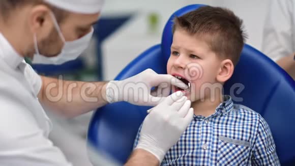 在牙医检查牙齿时坐在扶手椅上的男孩子4K红色相机拍摄视频的预览图