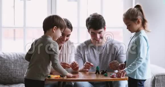 快乐的年轻父母和在家里雕刻面团的小孩视频的预览图