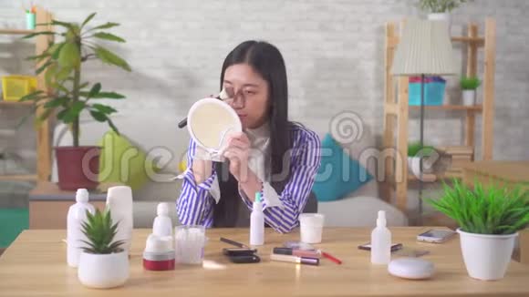 一位在客厅化妆的亚洲年轻女子的肖像视频的预览图