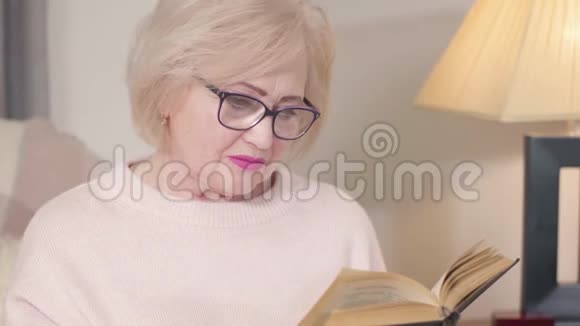 特写浓白种人老女人的肖像看书转向相机和微笑成熟的女人视频的预览图