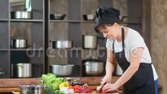 微笑的女厨师在餐桌上切鲜肉准备食物红色相机宽镜头视频的预览图