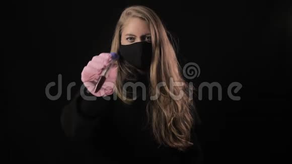 戴着黑色面具的女孩拿着一根带血的试管上面写着Covid19孤立在黑色背景上健康视频的预览图