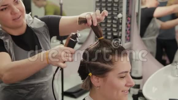专业的理发师女士用剪发器剪发给客户视频的预览图