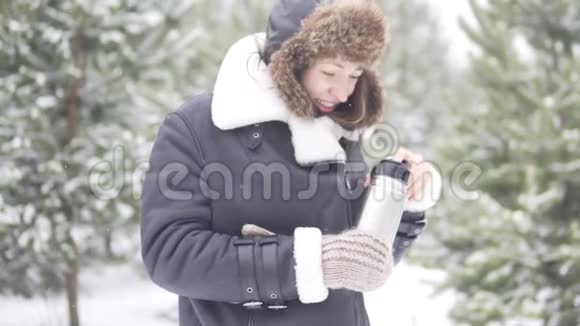 冻僵的女人在冬天散步时从热水瓶里倒温茶视频的预览图