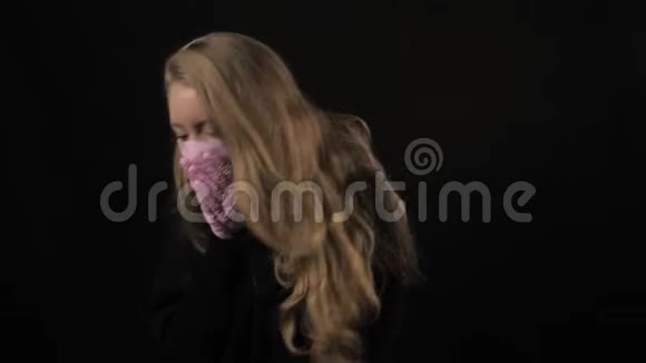 穿粉色医疗面具的女孩咳嗽孤立在黑色背景上保健和医疗理念特写肖像4k视频的预览图
