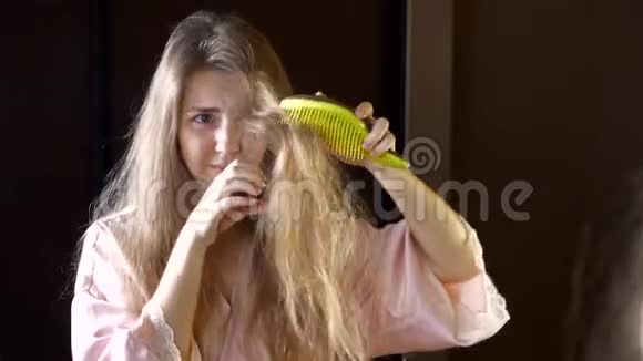 头发干脆的不开心的女人在镜子里检查她缠结的头发视频的预览图
