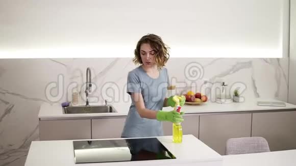 白种人女孩在厨房里清洁烹饪面板年轻女子清洁黑色陶瓷的完美表面视频的预览图