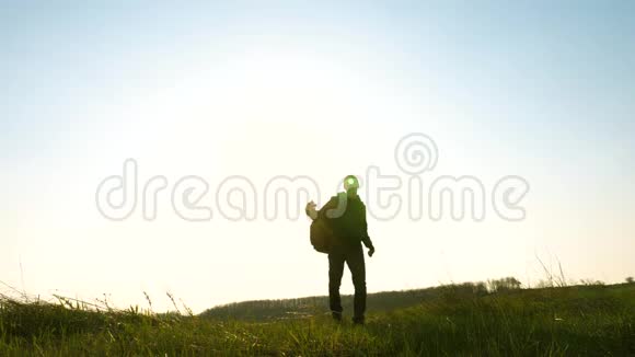 有趣的旅行者带着背包走来走去一位背着背包的游客在明亮的田野里漫步视频的预览图