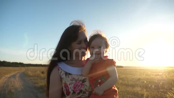 快乐的妈妈抱着孩子散步妈妈和小女儿正走在麦田里的乡间小路上视频的预览图