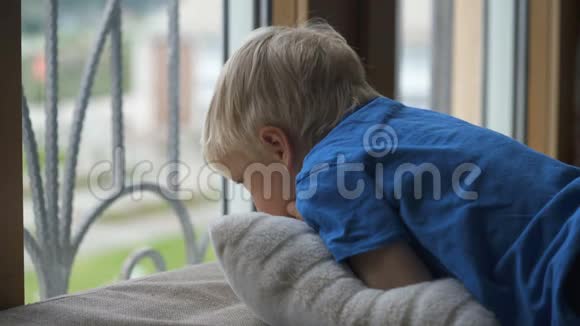 呆在家里预防检疫冠状病毒大流行四岁男孩透过窗户看不到视频的预览图
