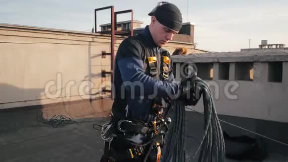 穿制服的工业登山者站在高层建筑的屋顶上手里拿着长长的安全绳视频的预览图