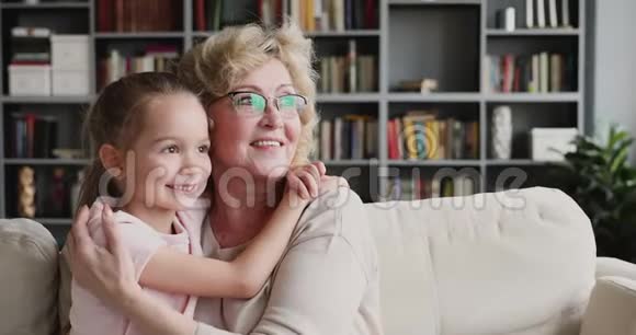 微笑的老奶奶抱着可爱的孙女看着远方的梦视频的预览图