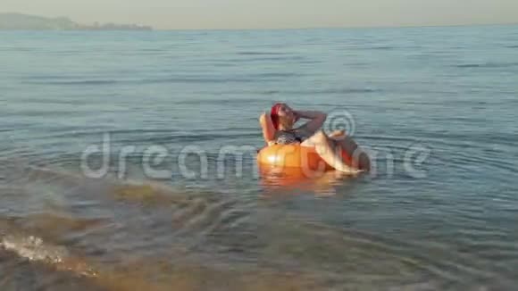 一个穿着泳衣的女人在游泳圈的海浪上晒太阳视频的预览图